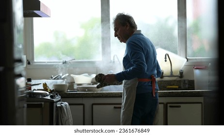 Candid senior chef cook standing by kitchen counter preparing meal, genuine older man preparing food pouring boiling water into sink, daily domestic culinary routine - Powered by Shutterstock