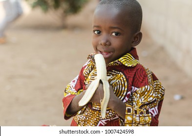 Candid Shot Of African Black Boy Eating Banana Outdoor