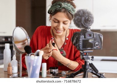 Candid Shot Of Charming Young Lady Video Blogger Talking On Mass Market Cosmetics Swatching Lip Gloss At Home, Sharing Tips And Recommendations On Which Beauty Products Choose Via Social Networks