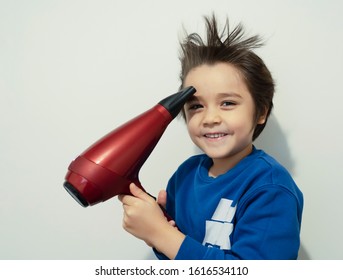 Candid Shot, Cute Kid Drying His Hair With Hair Dryer, Cheerful 6 Years Old Boy Try To Making His Hair Like A Crazy Expression, Flying Hair, Lightness And Happiness. Concept Child Care Concept