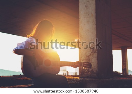 Candid silhouette woman chill play acoustic guitar musician 
Artists female sad mood activity music 
at balcony flare lighting sunset background