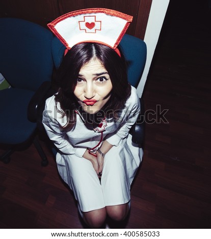 Candid snapshot of a young adult woman disguised as a nurse goofing off in front of the camera.