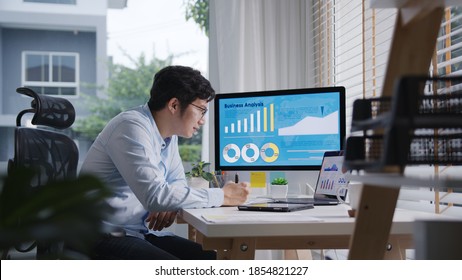 Candid Of Young Attractive Asian Thai Man Busy Work Multiple Screen Computer Or Smart Tablet On Table Desk At Home In Freelance Data Analyst, Data Science Scientist For Business.