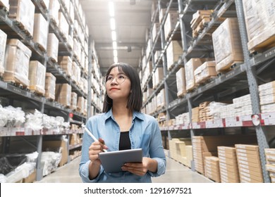 Candid of young attractive asian woman auditor or trainee staff work looking up stocktaking inventory in warehouse store by computer tablet with wide angle view. Asian owner or small business concept.