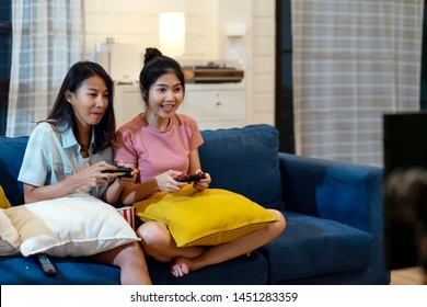 Candid Of Young Attractive Asian Women Or Friends Playing Video Game Laughing Happy And Sitting On Sofa Together With Fun And Copyspace. Game Competition Of Young Asian Girls Friends Or Family Sister.