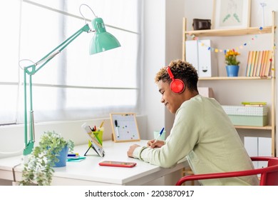 Candid Young Hispanic Latin Student Man Listening To Digital Online Course On Laptop. Smiling Hispanic Latin Teenage Boy Learning On Virtual Webinar. E-learning And Studying Online Concept