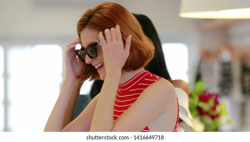 Candid young multiracial women trying on sunwear. Girls shopping for sunglasses