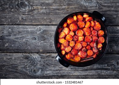 candied yams, thanksgiving sweet potatoes cooked with cinnamon, brown sugar and butter in a black ceramic dish, horizontal view from above, flatlay, free space