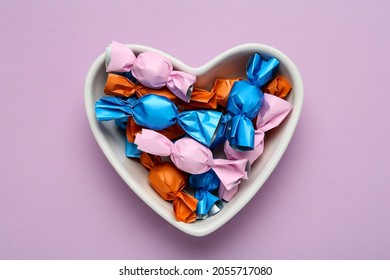Candies in colorful wrapper on pink background, top view