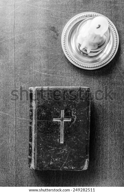 Candle and Bible on the wooden desk. In black and\
white tones