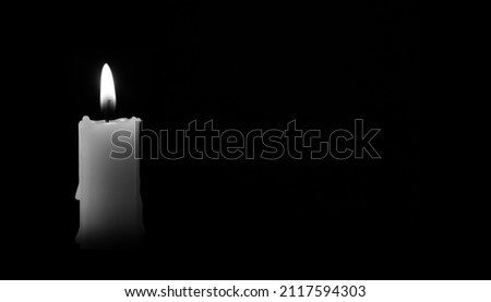Candle burning in the black background. There's room for your text. Black and white photo. The concept of mourn, grief or mourning