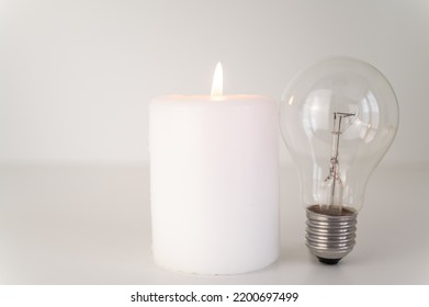Candle with burning flame, next to unlit bulbs. Energy saving and rationing. Increase in tariffs and energy crisis.
 - Shutterstock ID 2200697499