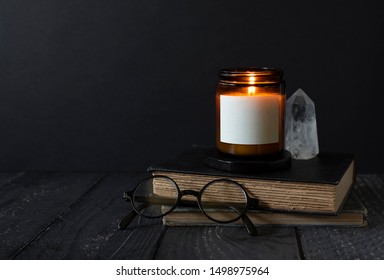 Candle Burning On Stacked Books, Reading Glasses, Crystal, Antique Books, Burning Scented Candle With Blank Label, Copyspace, Dark Background With Copy Space, Autumn Mood, Candle Label Design Mock Up