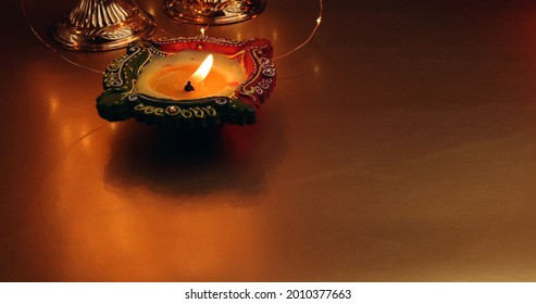 A Candle Burning In A Red-green Ornamented Candlestick Base On The Table; Deepavali Festival