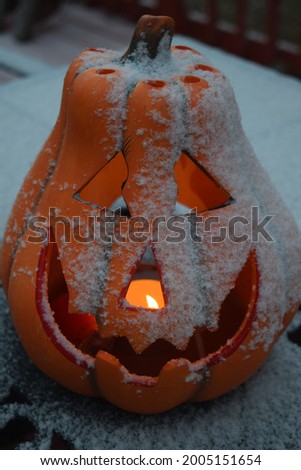 Candle burning in a snow covered jack o lantern