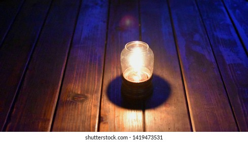 Candle In A Glass Lampshade On A Wooden Background.