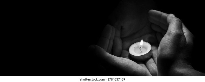 Candle in hand burning on the black background.