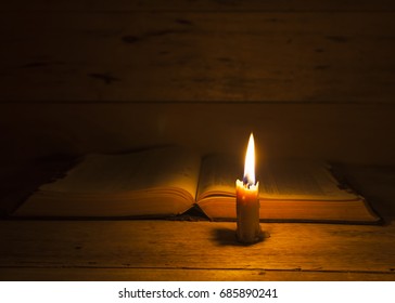 candle light with over open bible book in the night
