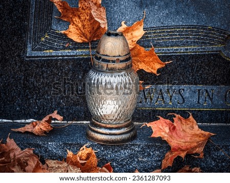 candle on a grave covered with dry autumn leaves.  All Saints Day 1st November. All Souls Day 2nd November. The Day of The Dead.