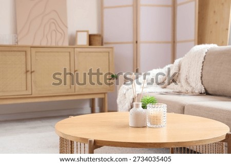 Candle and reed diffuser on table in interior of living room, closeup
