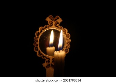 The candle seen reflected in the mirror. Candlelight reflected in the mirror in the dark. - Shutterstock ID 2051798834