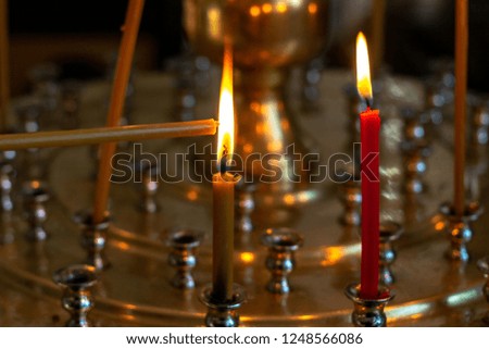 The candle is set on fire. Candles burn in the church on a special stand.