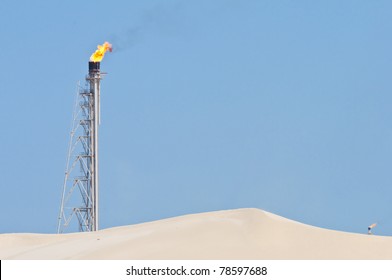 A Candle Tower Burning Off Excess Gas At An Oil Refinery In The Desert.