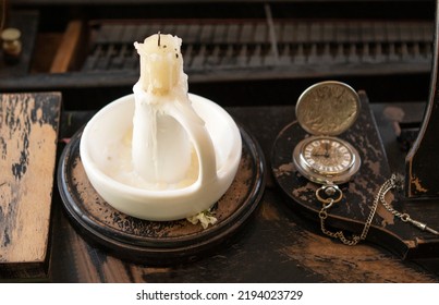 A Candle In A White Candlestick And An Old Clock