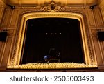 Candlelight piano concert, with a piano in the middle of the stage and candles around it emitting light. There are gold decorations around the stage and a black background behind the piano. 