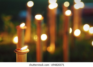 Candlelight Of Small Ceramic Candle Bowls Placed On Top Of Bamboo Sticks In A Lawn Or Garden.  Selective Focus And Blurred Background.