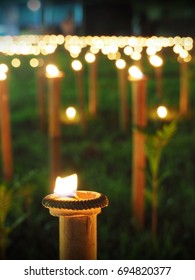 Candlelight Of Small Ceramic Candle Bowls Placed On Top Of Bamboo Sticks In A Lawn Or Garden.  Selective Focus And Blurred Background.