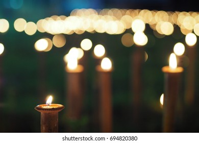 Candlelight Of Small Ceramic Candle Bowls Placed On Top Of Bamboo Sticks In A Lawn Or Garden.  Selective Focus And Blurred Background.