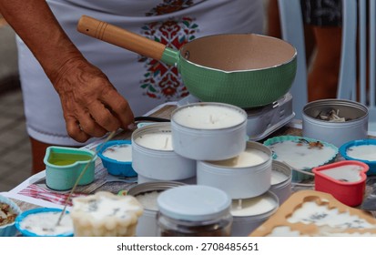 Candle-making master class highlights hands pouring melted wax into vibrant containers, demonstrating the craft of creating personalized scented candles with copy space