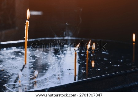 Candles burning, casting warm light and reflections, symbolizing spirituality, prayer, and hope in a church setting