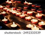 Candles burning in cathedral. Votive candles glows in the church. Prayer lighted candles in a catholic church.  