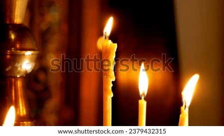 Candles burning in the church in the dark on the background of a cross. Church service. Church sacraments, prayer. Wax dripping down a burning candle