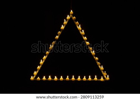 Candles are burning in a triangle in a dark studio          
