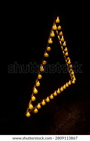 Candles are burning in a triangle in a dark studio          