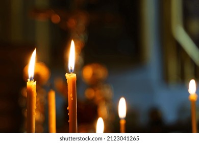 Candles in a Christian Orthodox church background. Flame of candles in the dark sacred interior of the temple