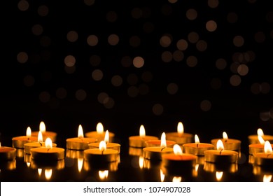 Candles in the dark with reflection and shallow depth of field, with lights in the background