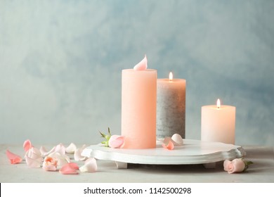 Candles with floral decor on table against color background
