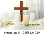 Candles, flowers and cross on light background