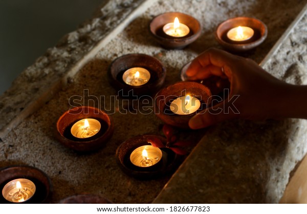 Candles light background with young woman hand\
taking one candle. Be the light and light the world concepts. Holy\
Saturday concept.
