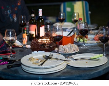 Candles Light And Messy Table With Food And Alcohol During A Night Party