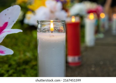 Candles lined up in a row on a sidewalk during a vigil to honor a person who died