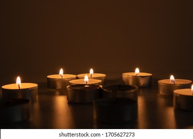 Candles lit in the dark, and one candle unlit, sad and tragic scene - Shutterstock ID 1705627273