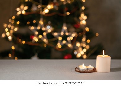 Candles on empty beige table, defocused Christmas tree with sparkling garland lights on background, festive holiday backdrop. - Powered by Shutterstock