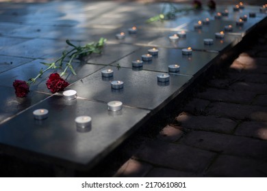 Candles On Gravestone. Wax Candles Burn On War Monument. Two Flowers On Tombstone. Burial Place Of Soldiers. Memorial Complex In Detail.