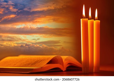 Candles and an open book as a symbol of religion. holy book on background of morning sky. Reading holy book. Concept - study of Bible or Koran. Reading religious literature. Opened Religious Textbook