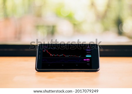 Candlestick chart showing the price of cryptocurrencies like Bitcoin on the sideway trend along with the bullish divergence of Relative Strength Index (RSI) indicator displayed on smartphone screen.